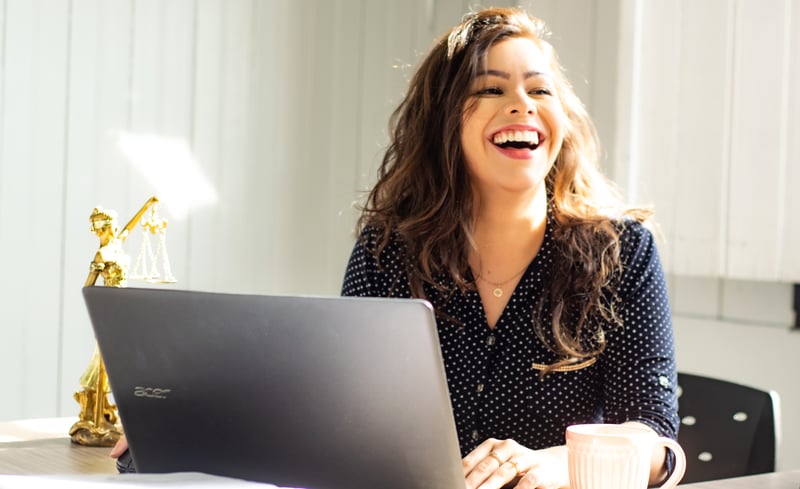 Woman Smiling Behind Laptop